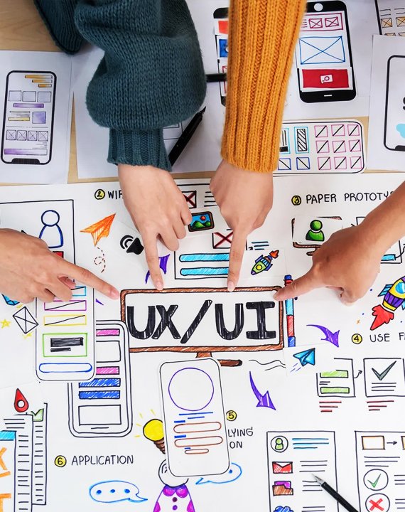 Team members pointing at colorful UX/UI sketches and wireframes on a table during a collaborative product design session.